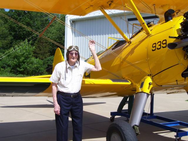 A Veteran poses with the Stearman Bi-Plane after taking a flight